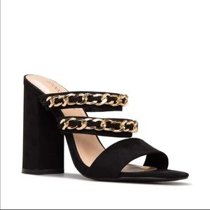Black heeled sandals worn gold chain details